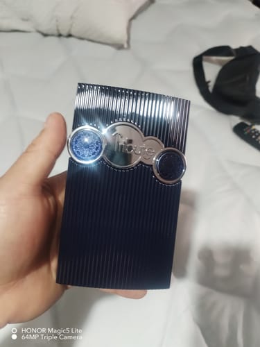 Cliente sosteniendo el frasco del perfume Afnan Tribute Blue en la mano sobre una superficie blanca.