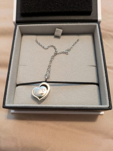 Reviewer's shiny Heart Urn Pendant necklace resting in its presentation box.