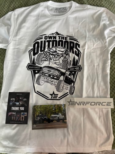 Customer's white ENR #84 Tee with a large graphic, laid out with an included card, photo, and sticker.