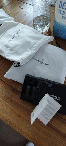 Reviewer's Fragrance Discovery Kit laid out on a table, showing the black box with samples and two white branded pouches.