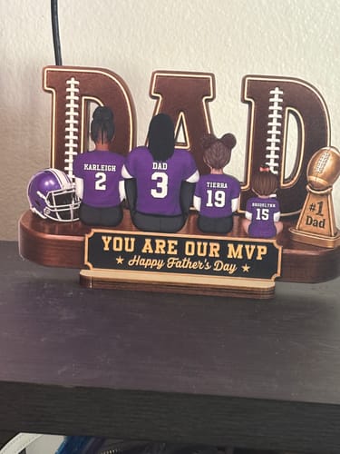 Customer's personalized wooden plaque for Father's Day, showing a family of four in purple football jerseys.