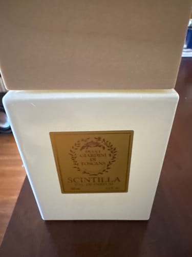 Cliente mostra il flacone luminoso dell'eau de parfum Scintilla con il suo tappo in legno.