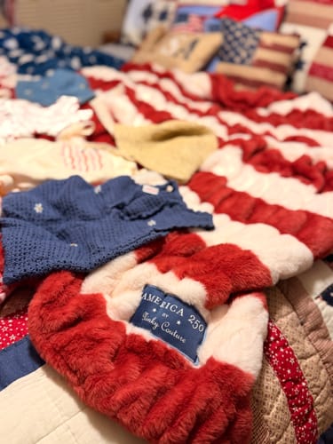 Customer's plush Hugs Flag Blanket on a bed, with a close-up on the soft stripes and the 'America 250' label.
