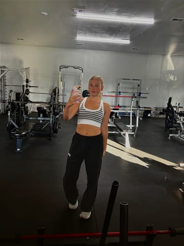 Reviewer standing in a gym showing the fit of the black Rebel Straight Leg Joggers.