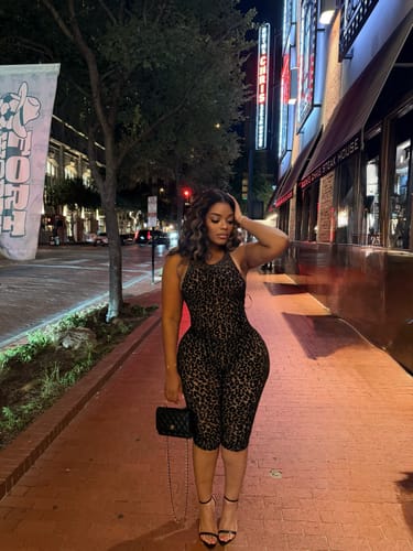 Reviewer posing in the burnout print halter capri jumpsuit on a city sidewalk at night.