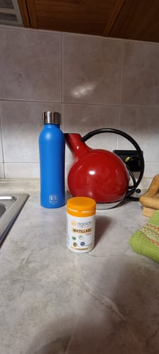 Recensore mostra il flacone di Mirtillase Forte sul bancone di una cucina.