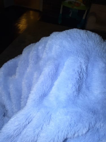 Close-up of a reviewer's soft, light blue Hugs Light Blanket showing its fluffy texture.