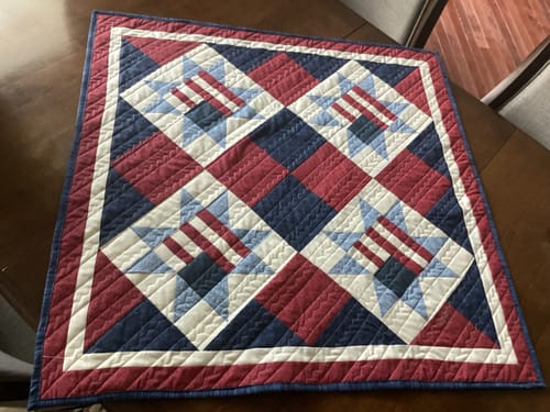 Reviewer's completed Land of Liberty table runner with its patriotic red, white, and blue pattern, lying on a table.