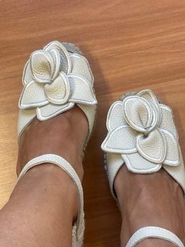 Una clienta muestra el ajuste de las Alpargatas Celia Crudo en sus pies, destacando el adorno de flor del empeine.