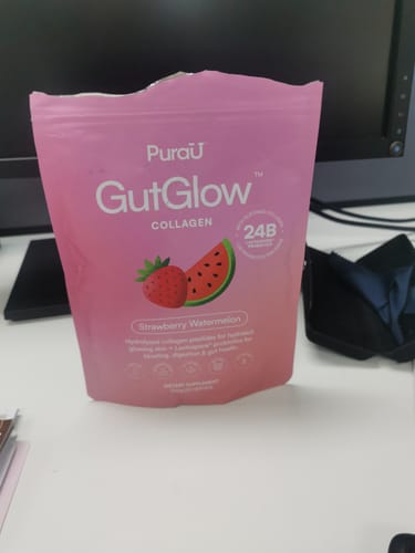 Customer's pink pouch of GutGlow Collagen in Strawberry Watermelon flavor sitting on a desk.