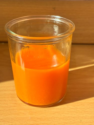 Kundenbewertung: Ein frisch zubereiteter, leuchtend orangefarbener Ingwer-Shot in einem Glas.