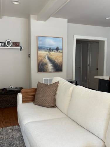 Reviewer's Sunlit Passage Canvas Art hung on a living room wall above a white couch.