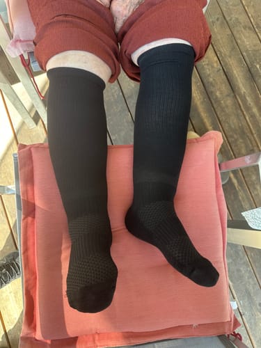 Recensent visar en närbild på en person som bär svarta Diasocks Stödstrumpor utomhus.