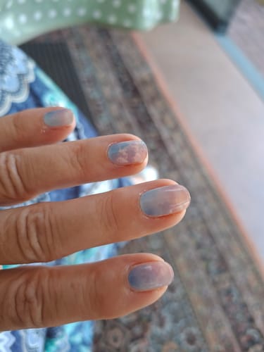 Nahaufnahme einer Kundenhand, die die Rainbow Vision UV-Gel-Nagelfolien mit pastellfarbenem Wolkendesign trägt.