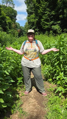 Customer wearing the 'I Love Peeing Outside' t-shirt while posing on a lush, green hiking trail.