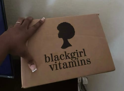 Reviewer holding the brown 'blackgirl vitamins' shipping box for their Gut Health Essentials.