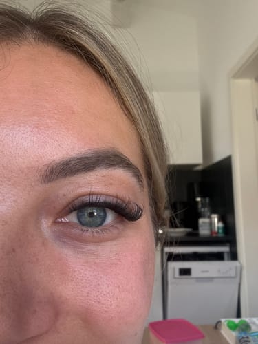 Nahaufnahme des Auges einer Kundin, das die langen, dichten Wimpernextensions von Pretty Press im Cat-Eye-Stil zeigt.