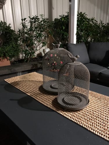 Customer's Joel Candle Cloche set on a woven runner on an outdoor table at night.