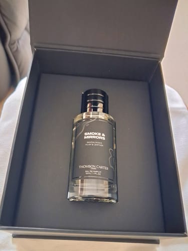 Customer's Smoke & Mirrors perfume bottle presented inside its elegant, dark grey packaging box.