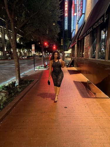 Reviewer walking down a city sidewalk at night wearing the burnout print capri jumpsuit.