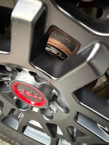 Close-up: Reviewer's installed 1.25" hubcentric wheel spacer visible through a gray wheel, showing slight surface rust.