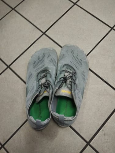 Ein Paar graue Smart I Barfußschuhe eines Kunden mit sichtbarem Fersenpolster und leuchtend grüner Innensohle.