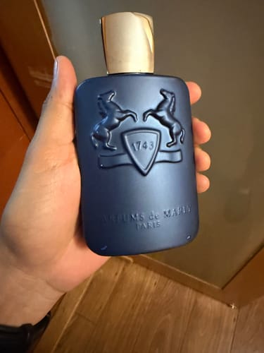 Cliente sosteniendo en la mano el frasco azul oscuro del perfume Parfums de Marly Layton.