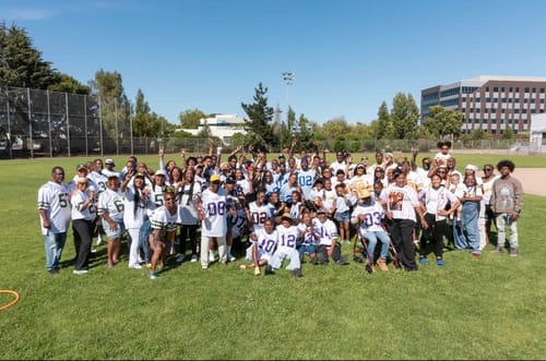 Customer's large family group posing on a field wearing custom white and blue football jerseys for a family day.
