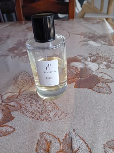 Le client montre son flacon de parfum FNR1 sur une table à motifs.