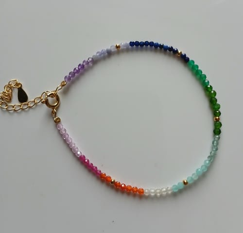 Photo d'un client du bracelet 7 chakras montrant les petites pierres multicolores sur la chaîne dorée.
