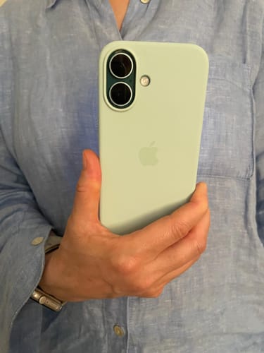 Customer holding their phone to show the back of the aquamarine Genuine iPhone 16 Silicone Case.