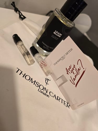 Reviewer's Lilium Blume Eau de Parfum, two perfume samples, and a card displayed on a branded white tote bag.