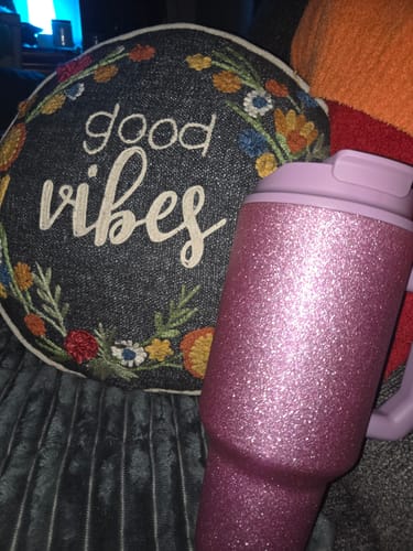 Customer's sparkly pink Thicc Buddy 50oz mug with a purple lid, shown next to a decorative pillow.