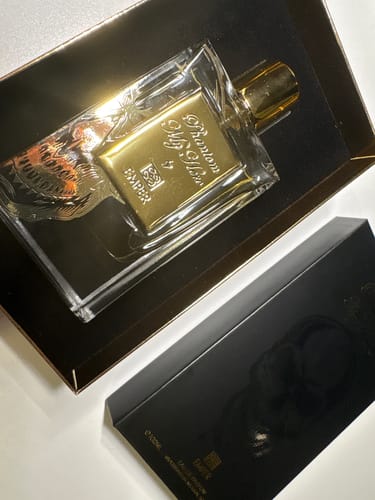 El cliente muestra el perfume Emper Phantom My Hero en su caja negra de presentación, revelando la botella con detalles dorados.