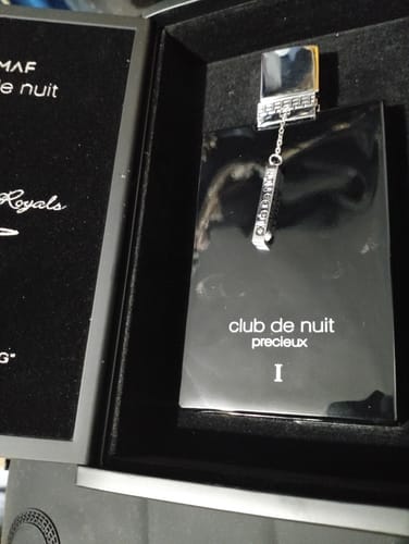 Cliente muestra un primer plano del perfume Club de Nuit Precieux I en su elegante caja de presentación negra.