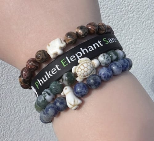 Reviewer's wrist stacked with multiple beaded bracelets, including The Journey Bracelet featuring a white sea turtle charm.