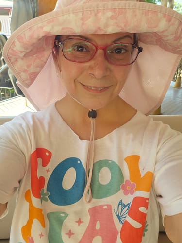 A customer smiling while wearing the white Cool Tias Club T-Shirt with a colorful graphic.