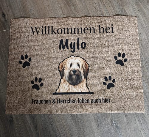 Kundenbewertung einer personalisierten Fußmatte mit Hundeporträt, dem Namen "Mylo" und Pfotenabdrücken auf einem Holzboden.