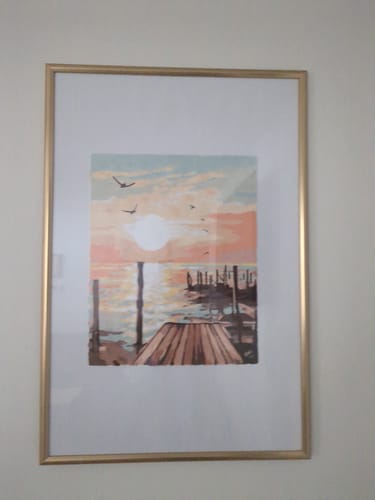Customer's finished Sunset Dock paint-by-numbers artwork, framed and hanging on a wall.