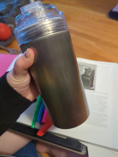 Reviewer holding the dark metallic Moonstone Universal XL shaker with a clear lid.