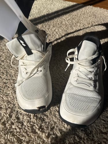 Reviewer's white CUURT Muuv court shoes, with one shoe cut at the toe and containing an AFO brace for a custom fit.