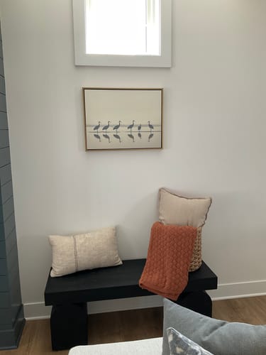 Customer's Sandhill Procession Canvas Art in a gold frame, hanging on a white wall above a black bench.