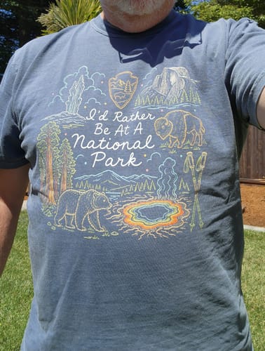 Customer wearing the blue 'I'd Rather Be At A Park T-Shirt' outdoors, showing the detailed graphic.
