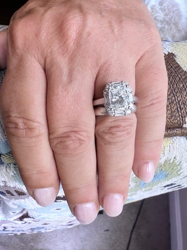 Customer's hand wearing the sparkling Doveggs halo vintage engagement ring with a large center stone.