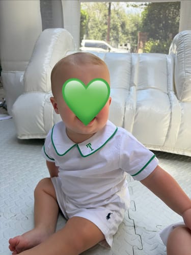 Reviewer's baby wearing the white undershirt with green trim, featuring a personalized green 'T' embroidered on the collar.