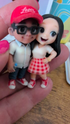 Customer holding a detailed custom figurine of a couple, intended for the display case.