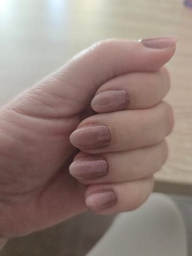 Hand einer Kundin, die die dezent schimmernden UV-Gel-Nagelfolien „Evening Out Ombré“ auf kurzen, runden Nägeln trägt.