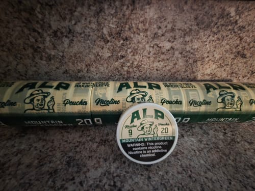 Customer's bulk sleeve and a single tin of Mountain Wintergreen Nicotine Pouches on a countertop.