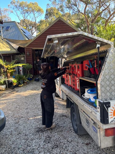 Reviewer wearing black wide-leg Construction Pants while getting tools from a work truck.