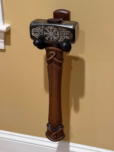 Customer's sturdy Wayfinder Hammer mounted on a wall, showing its engraved steel head and carved wooden handle.